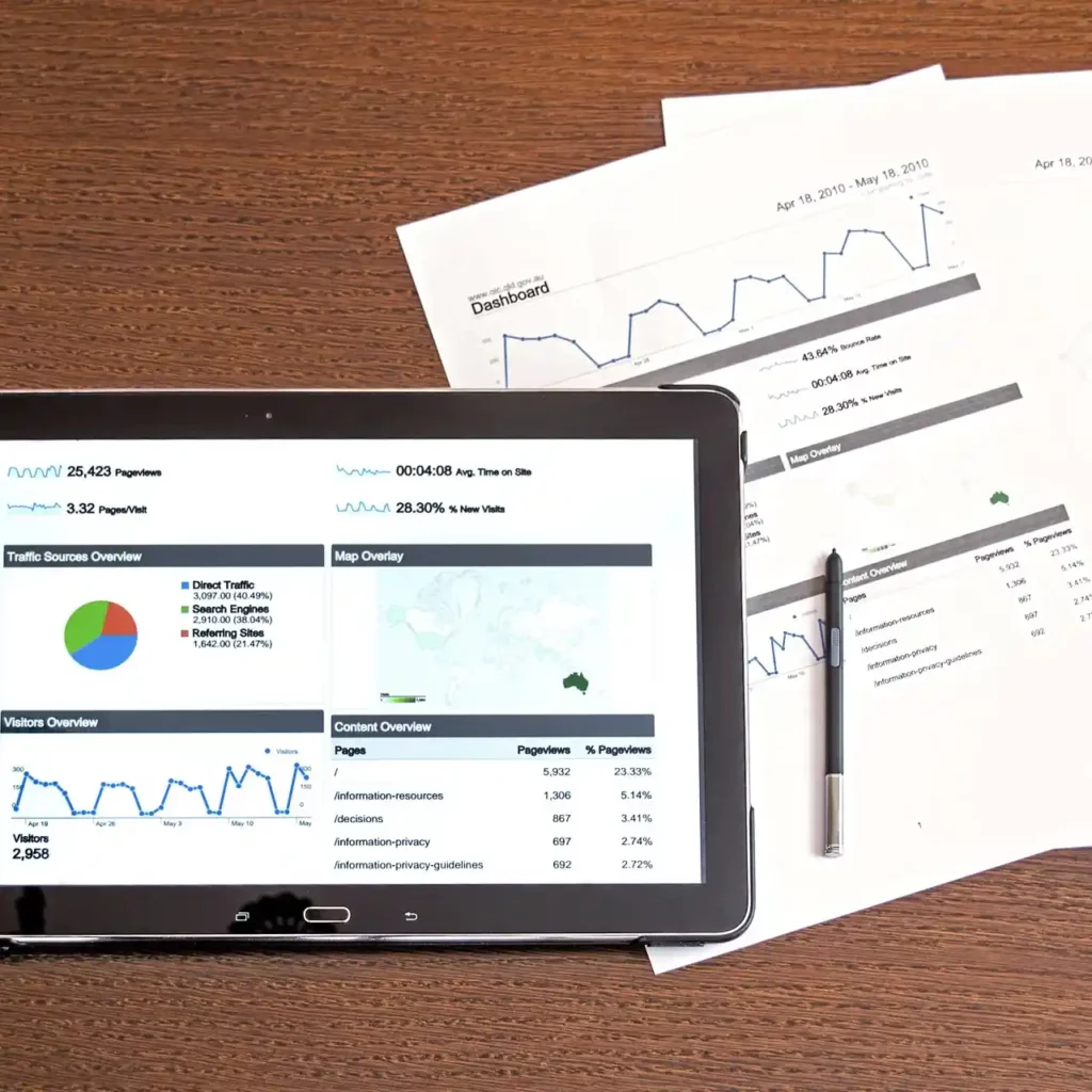 Tavolo con copra un tablet, una penna e un foglio di dati e grafici